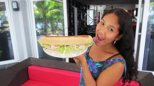 a young girl is holding a large sandwich at Binucot Beach Resort in Ferrol
