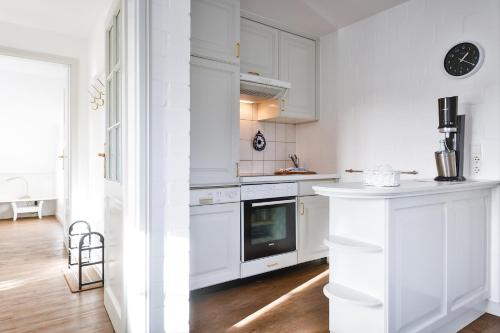 a kitchen with white cabinets and a stove top oven at Snetjers Hüs Appartement 13 in Hörnum
