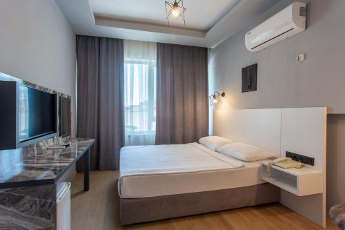 una camera d'albergo con letto e TV di Aslan Sand & City Hotel a Alanya