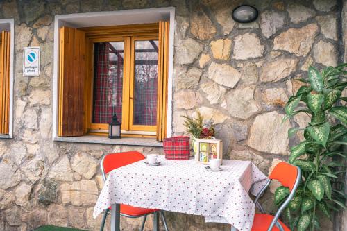 a table with red chairs sitting in front of a stone wall at [PRATO NEVOSO] Dépendance di montagna in Prato Nevoso