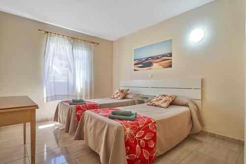 a hotel room with two beds and a table at Apartamentos las Góndolas in Playa del Ingles