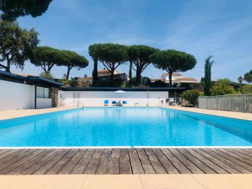 a large blue swimming pool with trees in the background at Villa-Golfe de Saint-Tropez/Accès plage privée in Grimaud