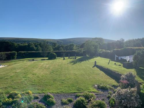 a large grassy field with the hills in the background at Gooseford Farm in Okehampton