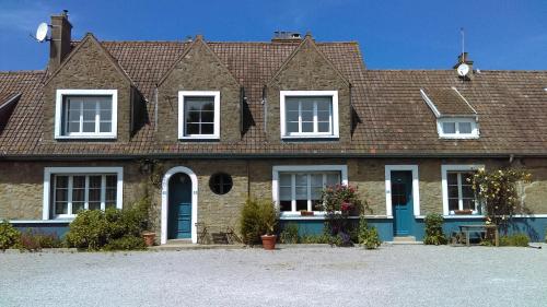 een bakstenen huis met witte ramen en blauwe deuren bij la clef des champs in Audinghen