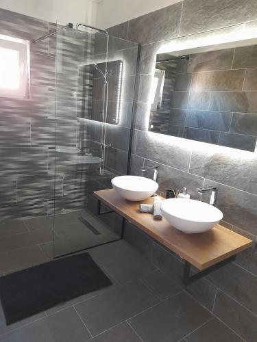 a bathroom with two sinks and a glass shower at sunny holiday in Vinišće