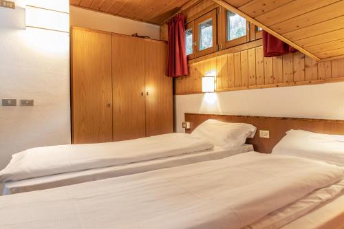 two beds in a room with wooden walls and windows at Hotel Italo in Madonna di Campiglio