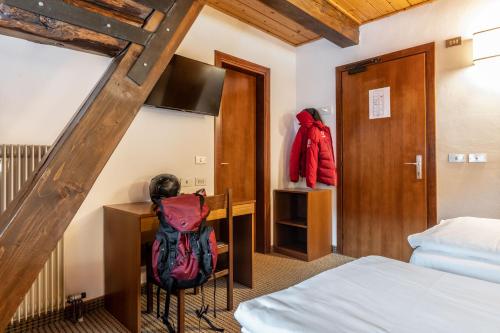 a bedroom with a bed and a desk with a backpack at Hotel Italo in Madonna di Campiglio