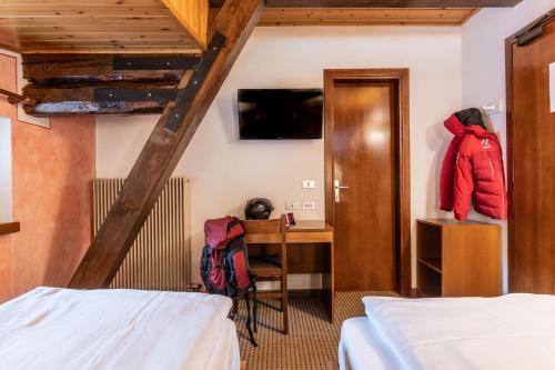 a room with two beds and a desk and a ladder at Hotel Italo in Madonna di Campiglio