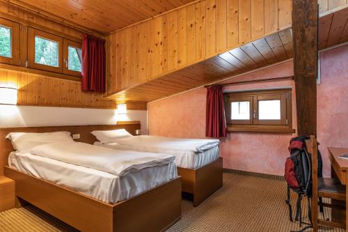 a bedroom with two beds and a desk and windows at Hotel Italo in Madonna di Campiglio