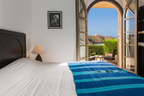 a bedroom with a bed and an open window at Auberge Dar Najmat in Mirleft