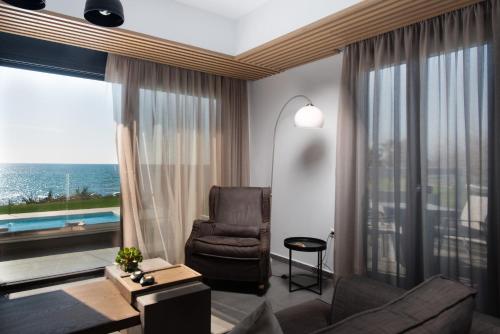 a living room with a chair and a large window at Mirazur Seafront Sunset Villa in Preveza
