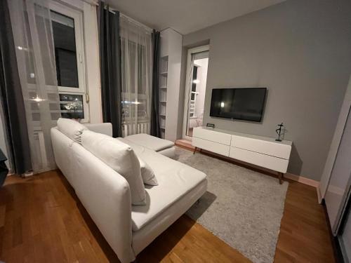 a living room with a white couch and a tv at Studio Ana Belville in Belgrade