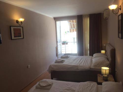 a hotel room with two beds and a window at Guest house Villa Slavica in Sveti Stefan