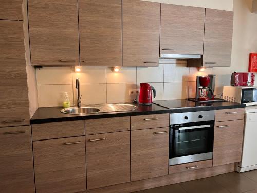 a kitchen with wooden cabinets and a sink at Maneschijn**** in Middelkerke