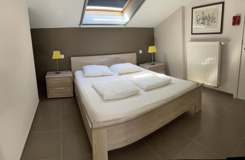 a bedroom with a bed with white sheets and pillows at Maneschijn**** in Middelkerke