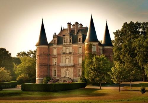 un grand château avec des tours sur une pelouse dans l'établissement Château D'Apigné Rennes, à Le Rheu