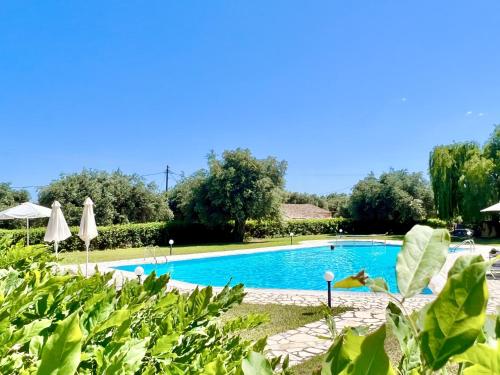 une piscine dans un complexe avec des arbres et des parasols dans l'établissement Barbati Blu & Verde Beach Houses with pool by DadoVillas, à Barbati