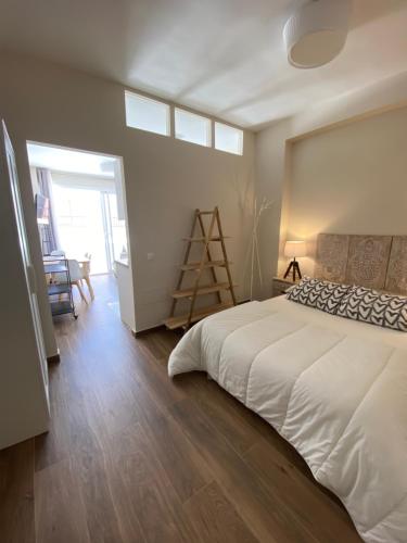 Schlafzimmer mit einem weißen Bett und Holzboden in der Unterkunft Apartamentos San Miguel in Torremolinos