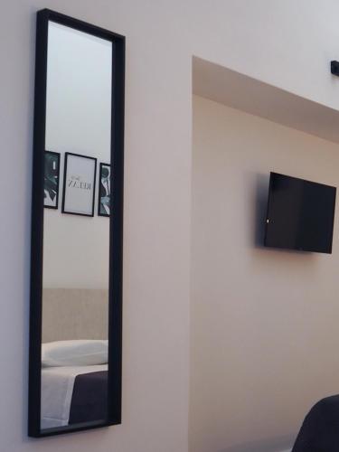a mirror hanging on a wall with a tv at DonPè in Agrigento