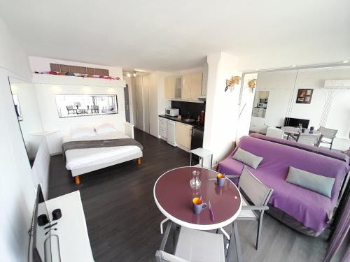 uma sala de estar com um sofá roxo e uma mesa em Studio Village Naturiste Résille em Cap d'Agde
