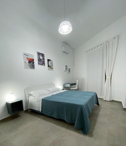 a white bedroom with a blue bed and a window at DonPè in Agrigento