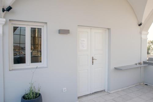 a white hallway with a door and a window at Central Hostel Oia in Oia