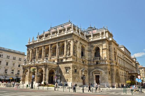 a large stone building with people walking in front of it at Mamaison Hotel Andrassy Budapest in Budapest