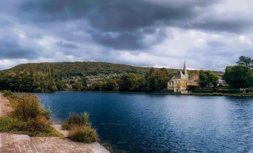 an island in the middle of a lake with a church at L'échappée au jardin, yourte bucolique in Godinne