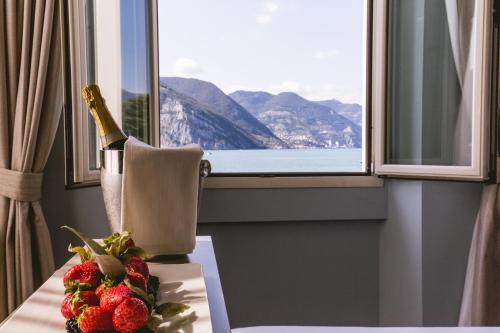 a bottle of champagne and strawberries on a table in front of a window at Araba Fenice Hotel in Iseo