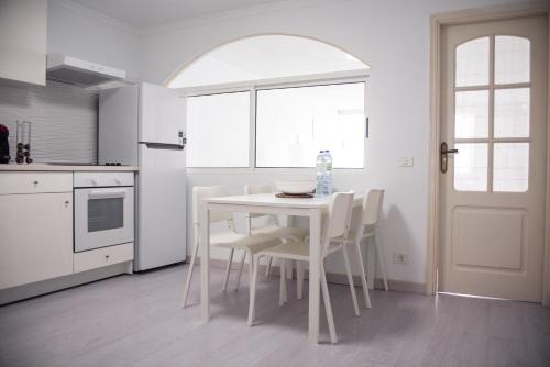 a white kitchen with a white table and chairs at SUNSET HOME wifi in Los Realejos