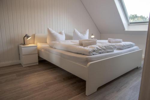 Cama blanca en habitación con ventana en Ferienwohnung-Haus-Ingeborg-Wohnung-3-OG, en Cuxhaven