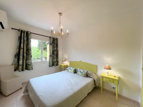 une chambre avec un lit, une fenêtre et un lustre dans l'établissement Résidence Marie Diane - Laurier Rose, à Propriano