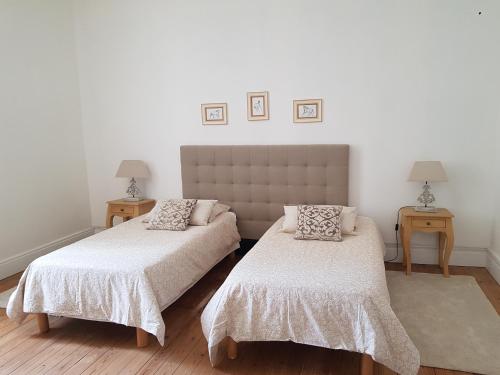 MonestierにあるDomaine et Manoir du Picaudのベッド2台、テーブル2台、ランプ2つが備わる客室です。