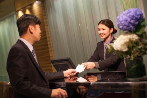 a woman handing a man a piece of paper at Park Hotel Hong Kong in Hong Kong