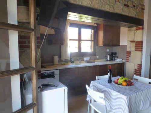eine Küche mit einem Tisch mit einer Flasche Wein und Obst darauf in der Unterkunft Pavloudis Apartments in Psakoudia
