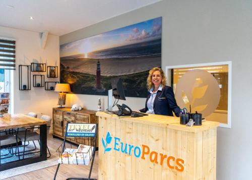 EuroParcs De Koog في دي كوكْسدوربْ: امرأة تقف في كونتر في غرفة