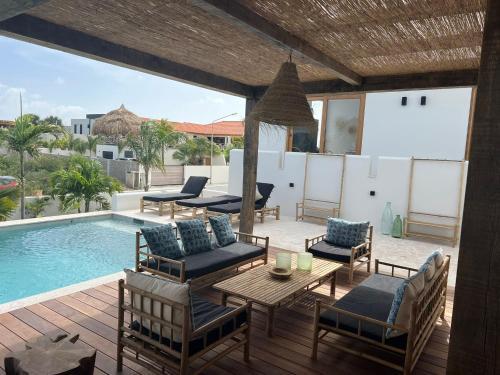 een patio met een tafel en stoelen naast een zwembad bij Villa Ban Kas Curaçao in Jan Thiel
