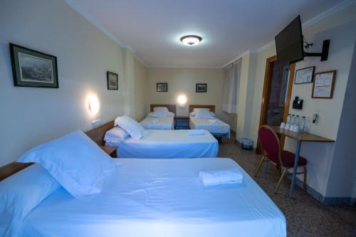 a hotel room with four beds and a television at Hotel Monasterio Granada - Adults Only in Granada