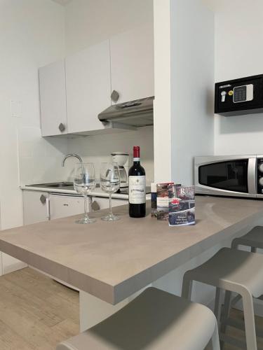 a bottle of wine and two wine glasses on a kitchen counter at Hotel Roma Aparthotel in Malcesine