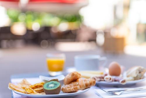 two plates of breakfast food on a table with orange juice at The Originals Résidence, Grenoble Université in Saint-Martin-dʼHères