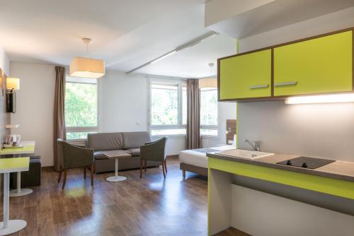 a living room with green cabinets and a couch at The Originals Résidence, Grenoble Université in Saint-Martin-dʼHères