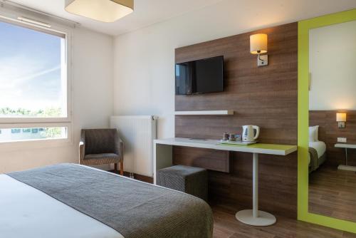 a hotel room with a bed and a desk and a tv at The Originals Résidence, Grenoble Université in Saint-Martin-dʼHères