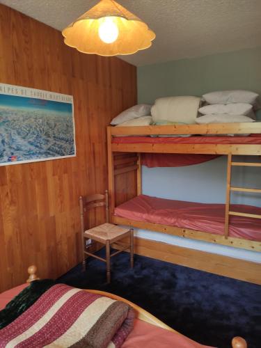 Un dormitorio con dos literas y una silla. en Appartement La Toussuire avec vue exceptionnelle, en La Toussuire