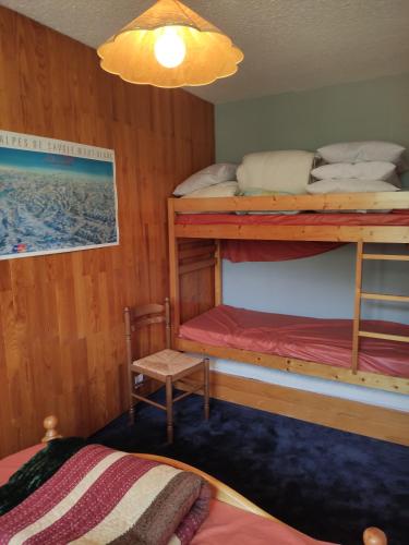 a bedroom with two bunk beds and a chair at Appartement La Toussuire avec vue exceptionnelle in La Toussuire