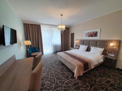 ein Hotelzimmer mit einem großen Bett und einem Tisch in der Unterkunft Ośrodek Uzdrowiskowy Świerkowy Zdrój Medical Spa in Rymanów-Zdrój