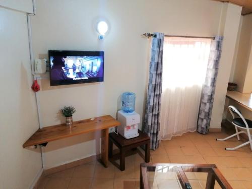 um quarto com uma mesa e uma televisão na parede em Penthouse Studio Apartment em Nairobi
