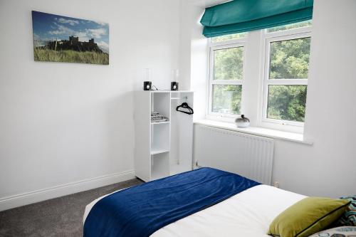 een slaapkamer met een bed en 2 ramen bij Beautiful cozy 3 bedroom 2 bathroom apartment in Newcastle upon Tyne