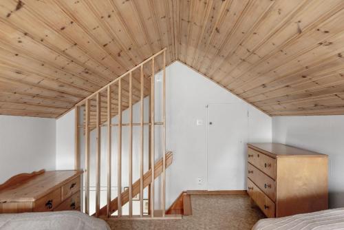 an attic bedroom with a wooden ceiling and a staircase at Nice cottage at Bolmstad Sateri by Lake Bolmen in Bolmsö