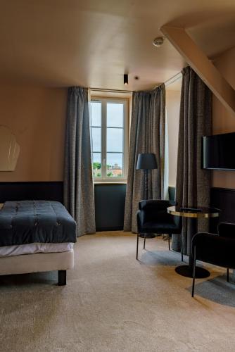 a bedroom with a bed and a desk and a window at Hotel de la Plage in Lion-sur-Mer