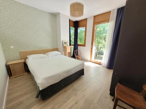 a bedroom with a bed and a large window at L'Appartement des Esclargies in Rocamadour
